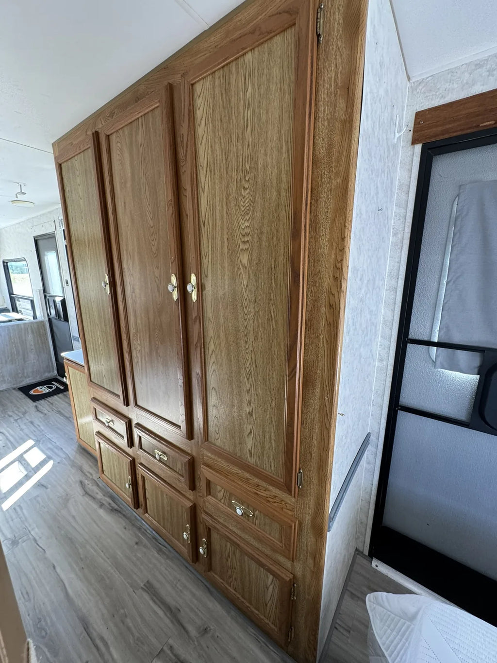 Grande armoire en bois avec portes et tiroirs dans la Sportsmen 3000, à côté d’une fenêtre.