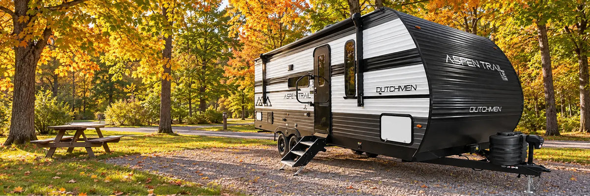 Roulotte Aspen Trail de Dutchmen sur un emplacement de camping en foret.