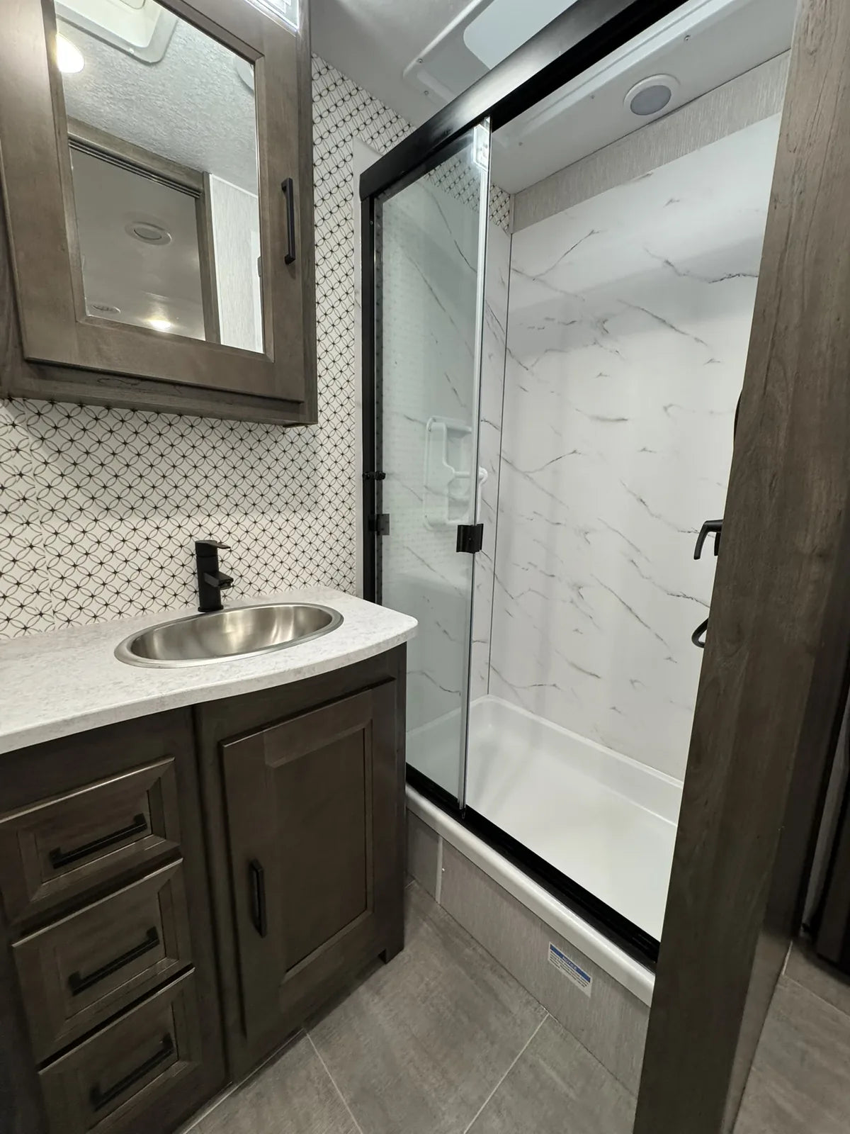 Douche vitrée attenante à la salle de bain.