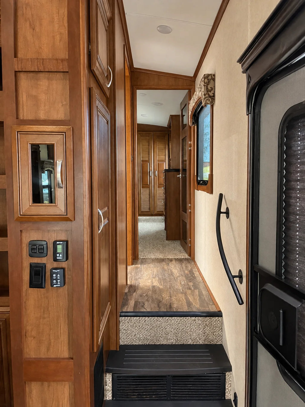 Corridor de la Jayco Pinnacle 36KPTS 2017 avec marches, main courante et armoires en bois menant à la chambre.