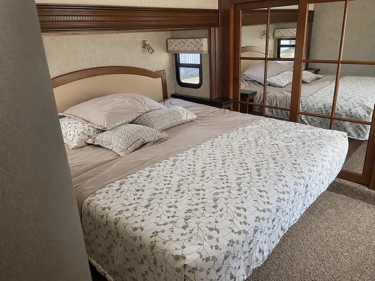 Chambre de la Jayco Pinnacle 36KPTS 2017 avec lit double, literie à motifs et garde-robe à portes miroir.