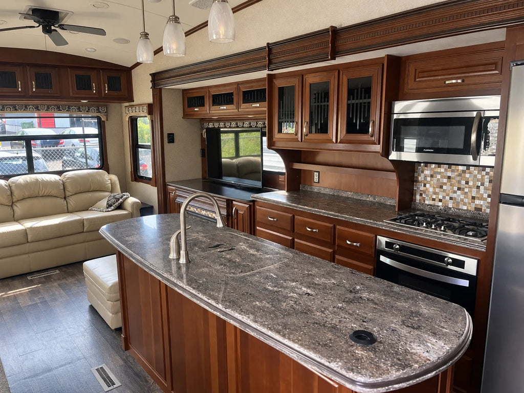Cuisine de la Jayco Pinnacle 36KPTS 2017 avec îlot central, robinet, cuisinière, micro-ondes et armoires en bois.