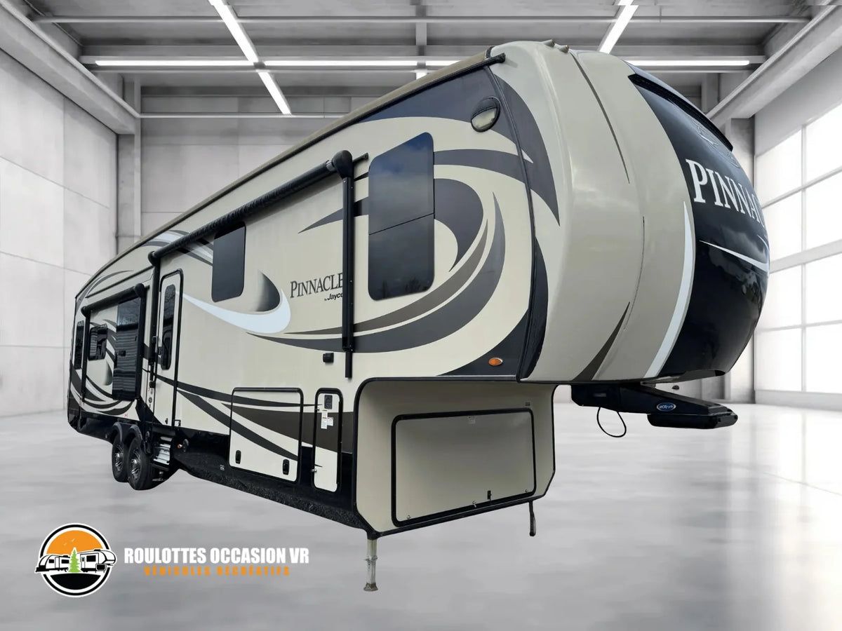Vue extérieure avant et côté entrée de la caravane à sellette Jayco Pinnacle 36KPTS 2017, présentée dans un garage avec le logo Roulottes Occasion VR.