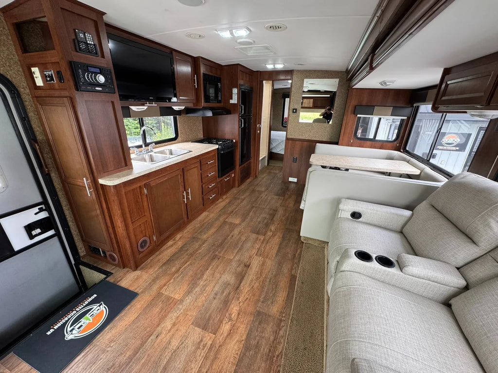 Salon du motorisé de classe A avec fauteuils, dinette et cuisine.