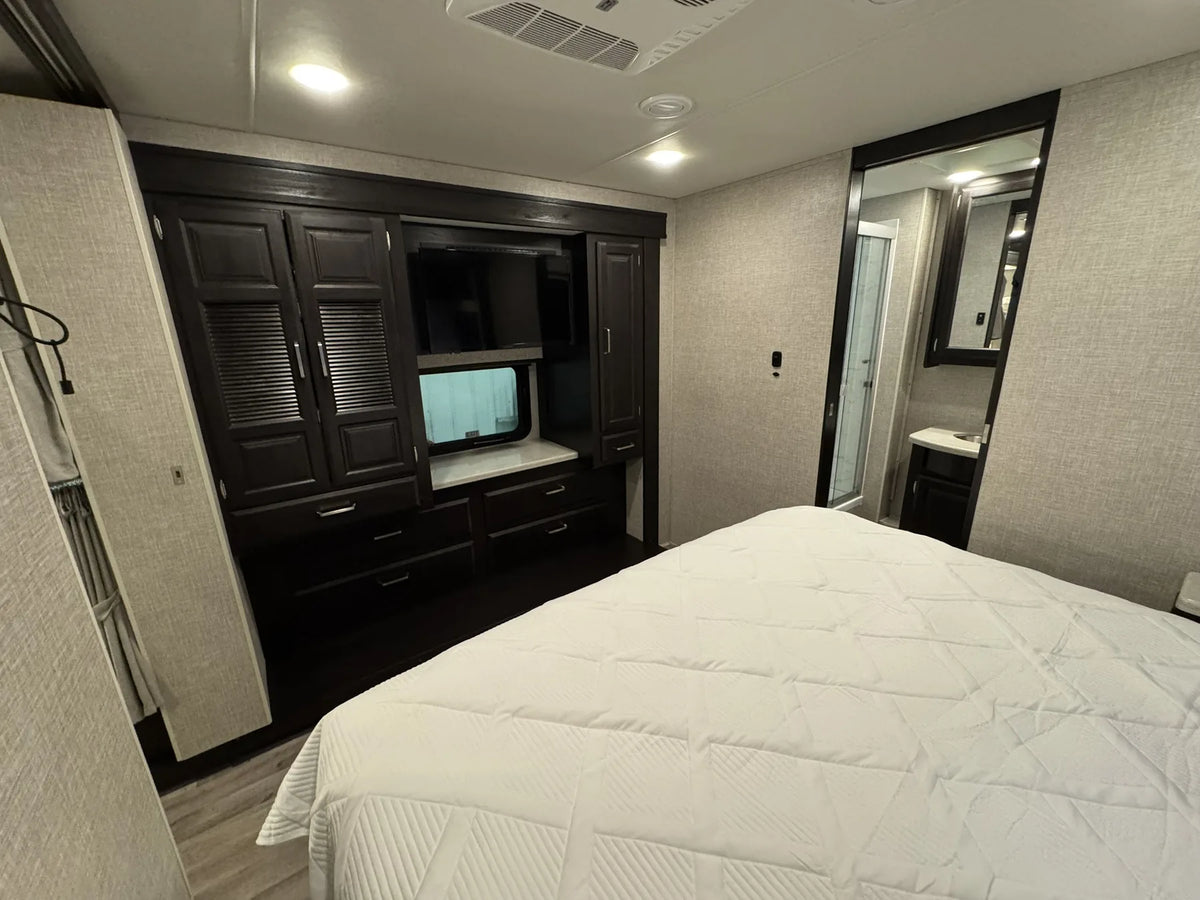 Chambre du motorisé Jayco Precept 36A 2023 avec lit, armoires et télévision.