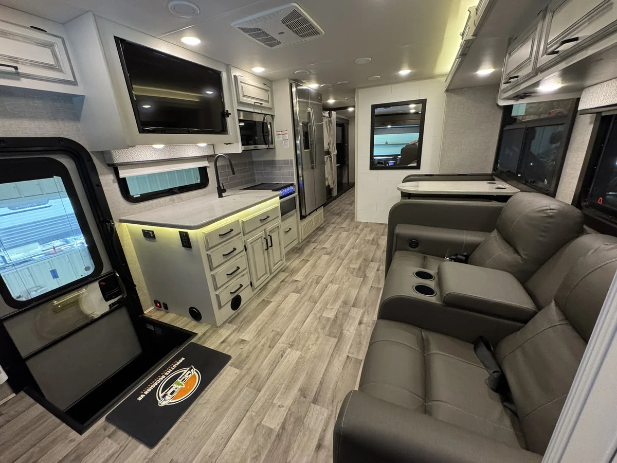 Salon du motorisé Jayco Precept 36A 2023 avec sofa, télévision et cuisine.