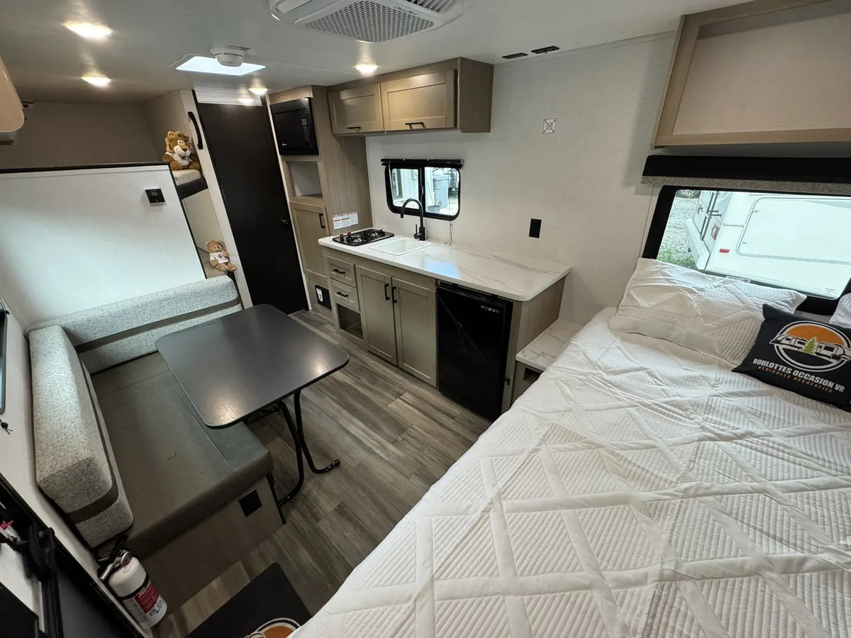 Vue intérieure de la roulotte Open Range Colt avec dinette, cuisine et lit principal