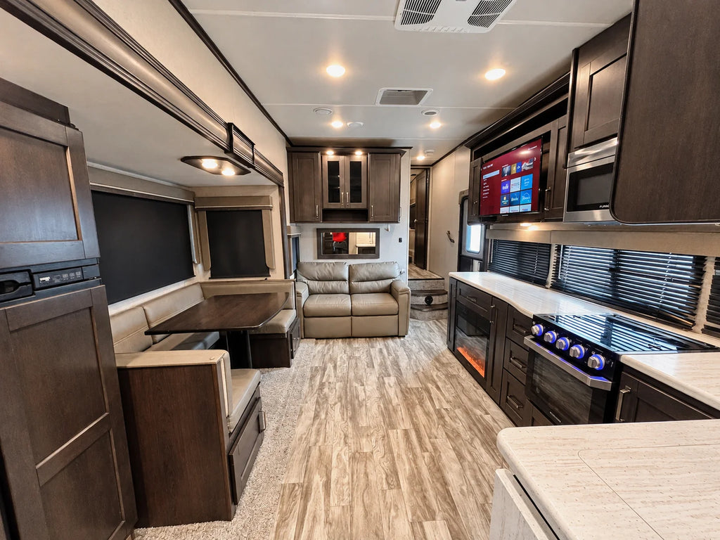 Intérieur de la Reflection 28BH 2021 avec cuisine, banquette en U, divan, téléviseur et foyer électrique.