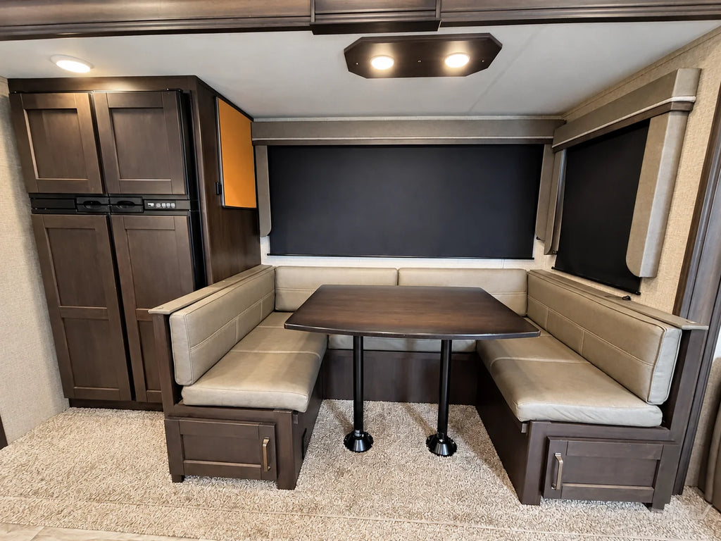 Banquette en U avec table et rangement sous les sièges dans la Reflection 28BH 2021, près du réfrigérateur.
