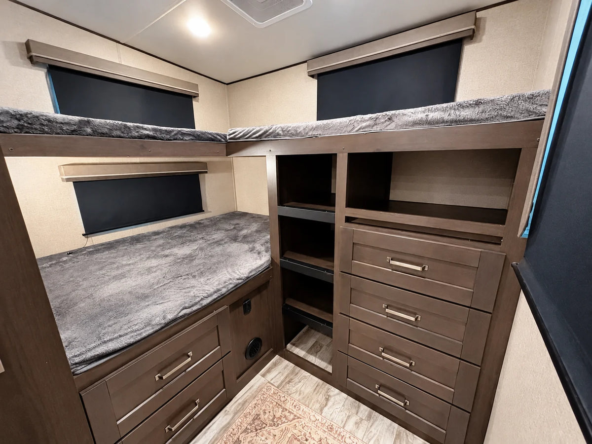Chambre arrière de la Reflection 28BH 2021 avec trois lits superposés, tiroirs et étagères de rangement.