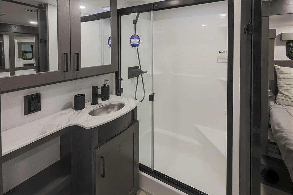 Salle de bain de la Alliance Valor 44V14 2024 avec douche fermée, lavabo et meuble de rangement.